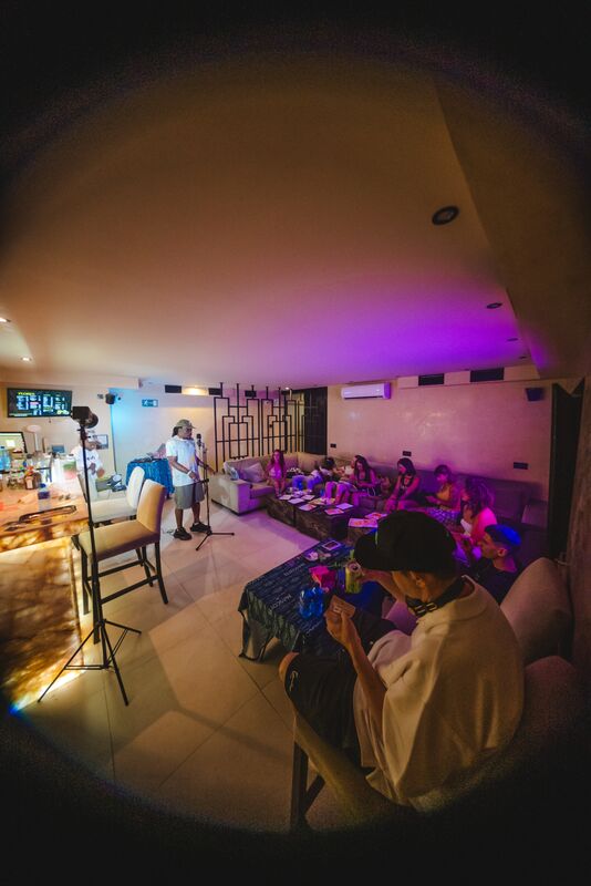A live set in the lounge, the room lit violet, everyone on the couches.