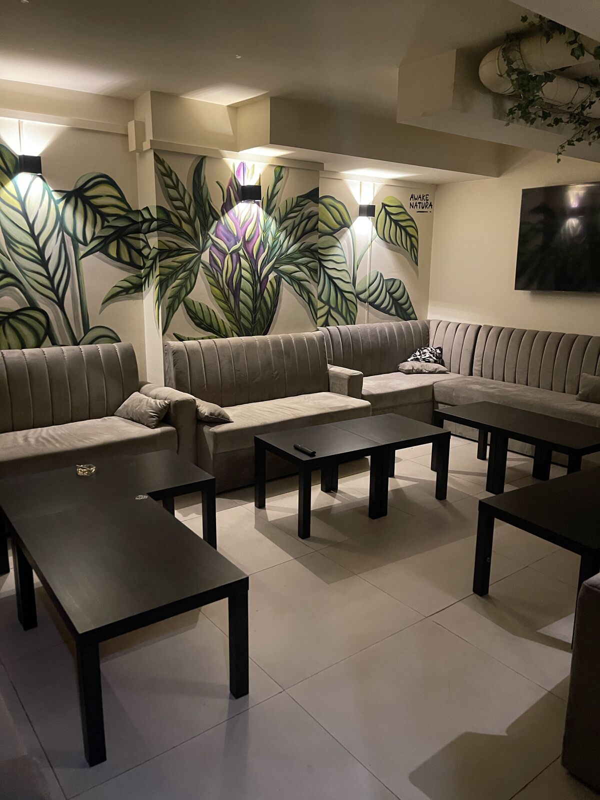 Upstairs: ribbed velvet banquettes, low black tables and a hand-painted botanical mural along the wall.