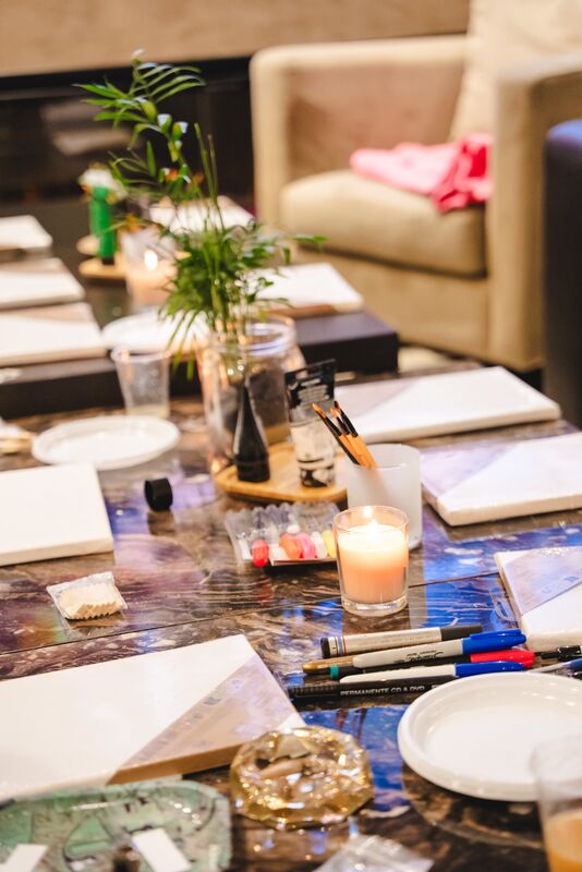 Blank canvases, brushes and candles laid out along the marble table before a painting workshop.
